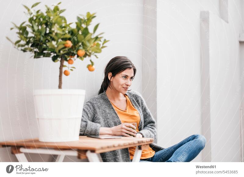 Woman relaxing next to orange tree sitting Seated portrait portraits woman females women smiling smile Adults grown-ups grownups adult people persons