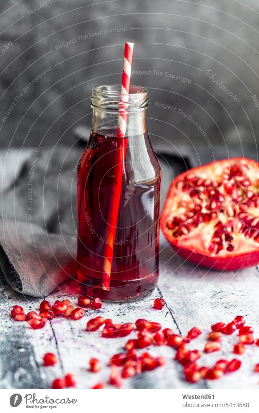 Glass bottle of pomegranate juice and sliced pomegranate Juice Juices fabric fabrics cloth nobody copy space wooden juicy straw straws drinking straw