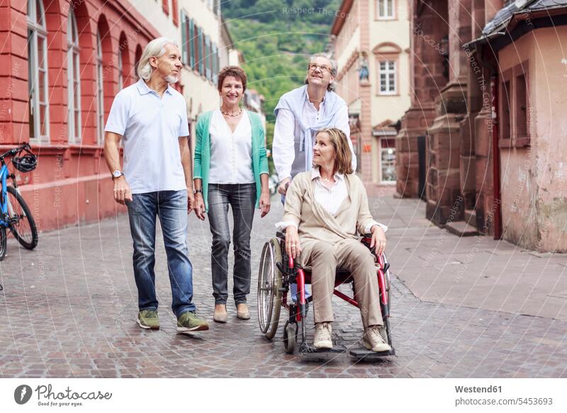 Germany, Heidelberg, senior friends with woman in wheelchair on city trip wheelchairs smiling smile senior adults seniors old friendship Adults grown-ups