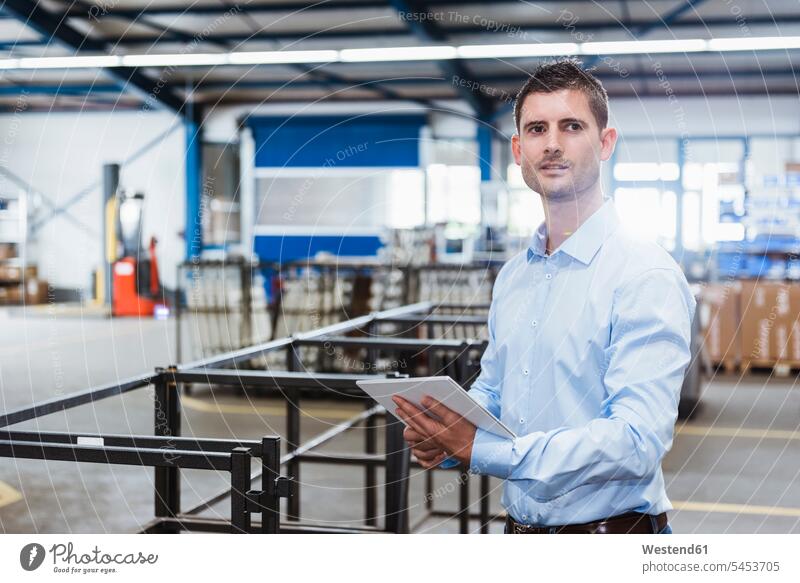 Young man working in shop floor, using digital tablet standing employee clerk employees clerks factory production hall products Businessman Business man
