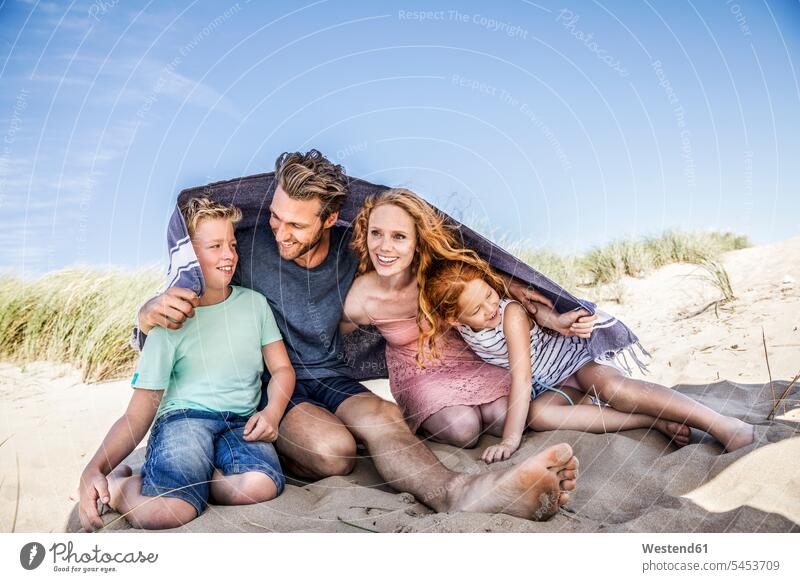 Netherlands, Zandvoort, happy family under a blanket on the beach smiling smile beaches families happiness people persons human being humans human beings