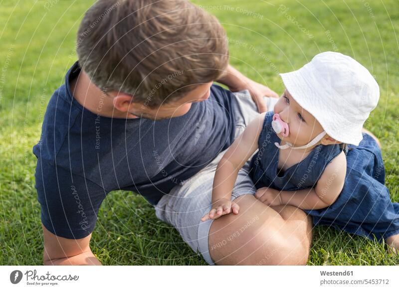 Father with little daughter on meadow happiness happy looking eyeing meadows family families father pa fathers daddy dads papa daughters relaxed relaxation view