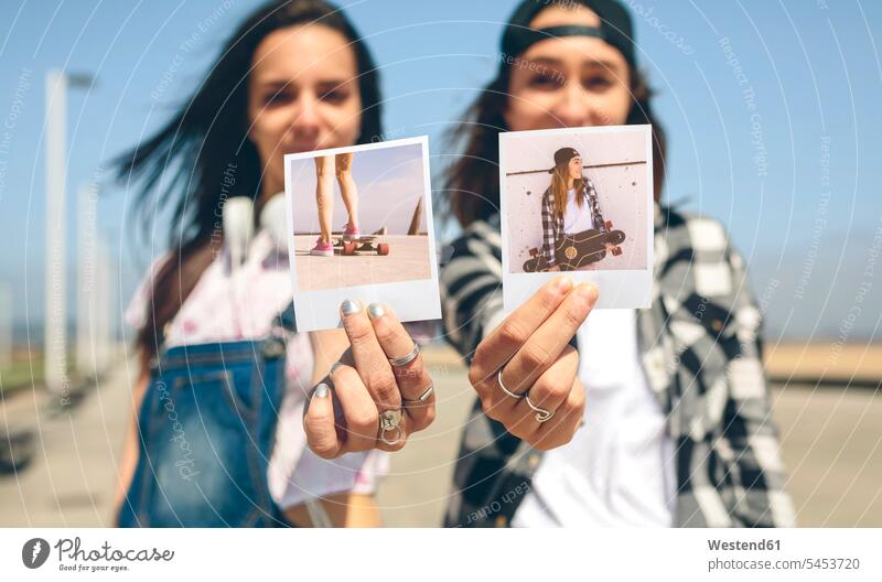 Two young women showing instant photos with their longboards caucasian caucasian ethnicity caucasian appearance european best friend bff best friends woman
