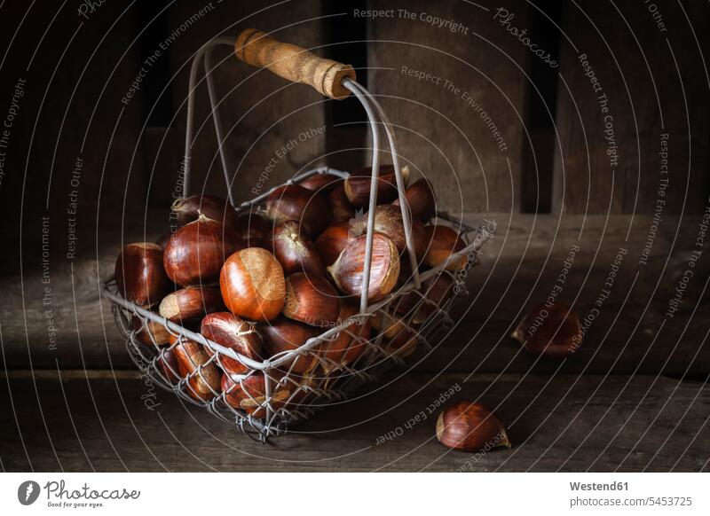 Sweet chestnuts in wire basket food and drink Nutrition Alimentation Food and Drinks shadow shadows Shades large group of objects many objects wooden copy space