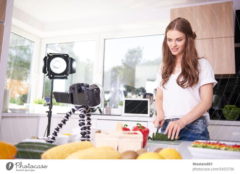 Woman recording while chopping a courgette cameras cook smile domestic kitchen kitchens human human being human beings humans person persons adult grown-up