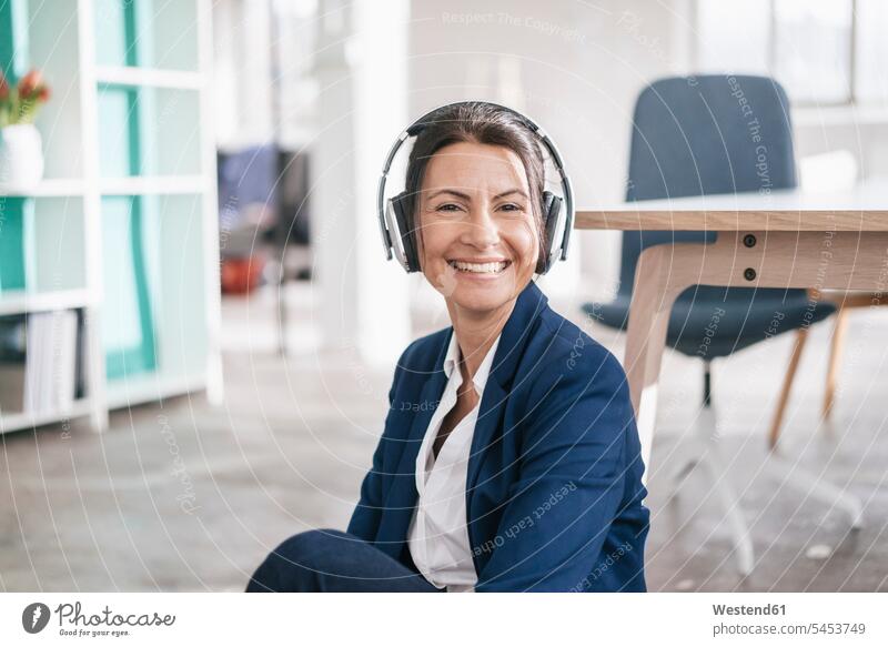 Portrait of happy businesswoman in a loft listening music with headphones portrait portraits females women businesswomen business woman business women headset