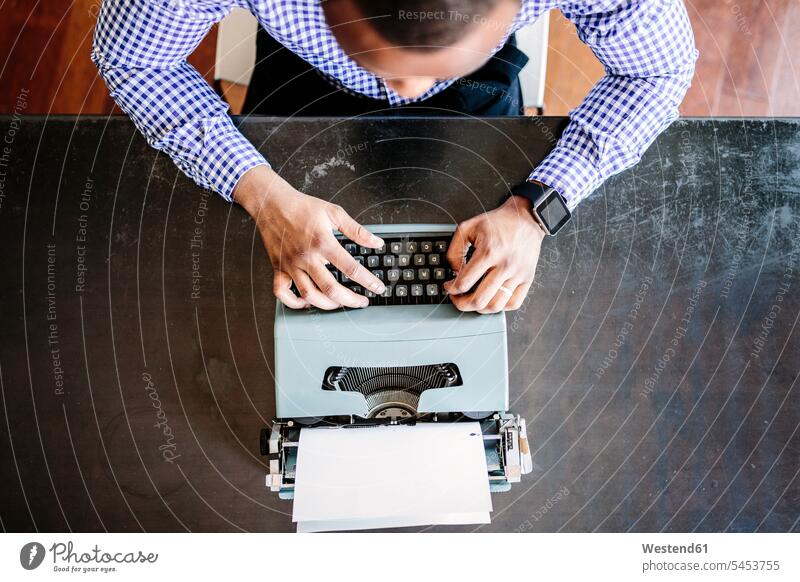 Young man at desk using typewriter men males desks typewriters Adults grown-ups grownups adult people persons human being humans human beings Table Tables