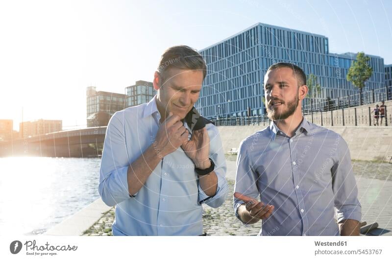 Two businessmen talking at the riverbank speaking colleagues Businessman Business man Businessmen Business men business people businesspeople business world