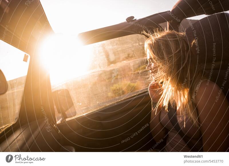 Blond woman with blowing hair sitting in car enjoying sunset windswept Hair Blowing blowing hairs blond blond hair blonde hair females women Seated automobile
