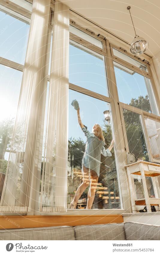 Woman cleaning the window in sunshine cleanse cleansing woman females women windows Adults grown-ups grownups adult people persons human being humans