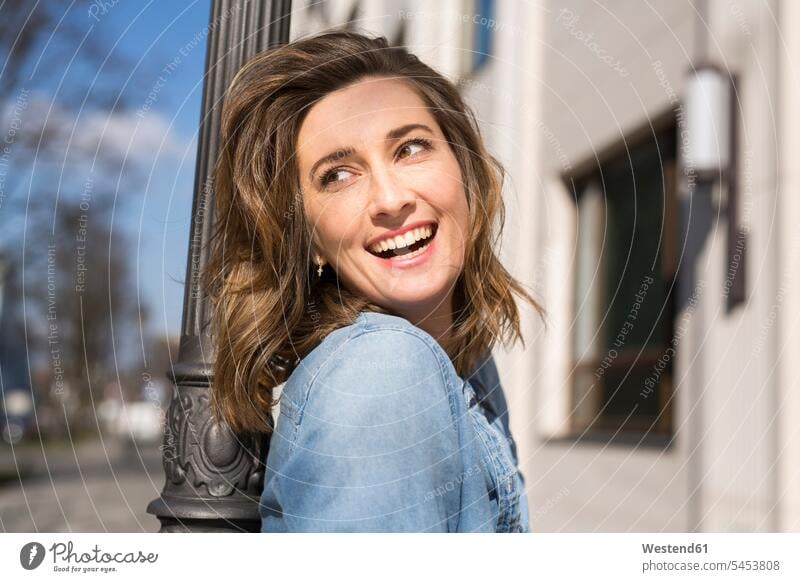Portrait of laughing woman leaning against lampe pole portrait portraits females women Adults grown-ups grownups adult people persons human being humans