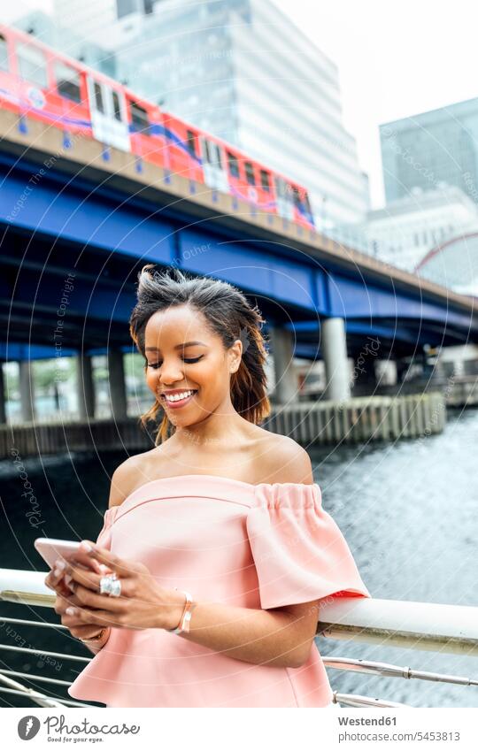 Smiling woman sending messages with her smartphone in the city smiling smile mobile phone mobiles mobile phones Cellphone cell phone cell phones females women