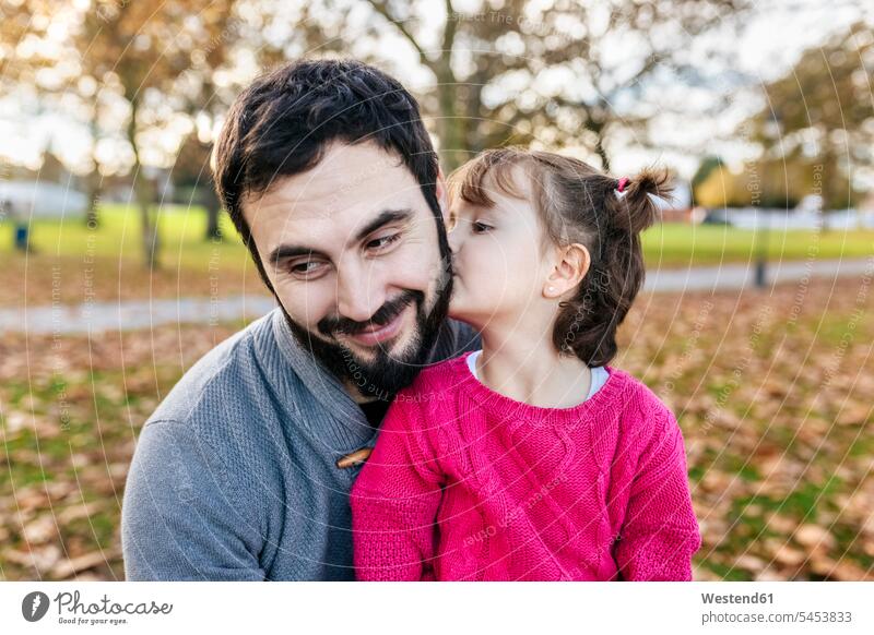 Little girl kissing her happy father in autumnal park kisses daughter daughters fathers daddy dads papa child children family families people persons