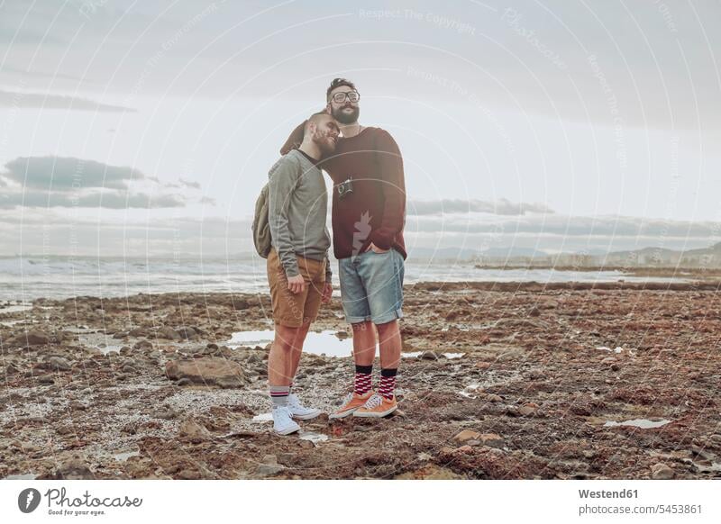 Happy young gay couple standing on the beach twosomes partnership couples beaches people persons human being humans human beings homosexual queer same-sex