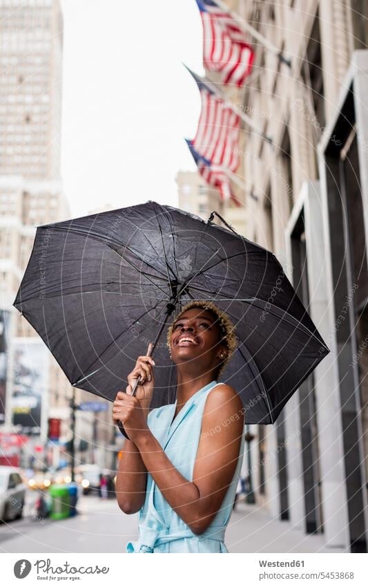 USA, New York, young blonde african-american woman with umbrella rain raining females women smiling smile Joy enjoyment pleasure Pleasant delight umbrellas