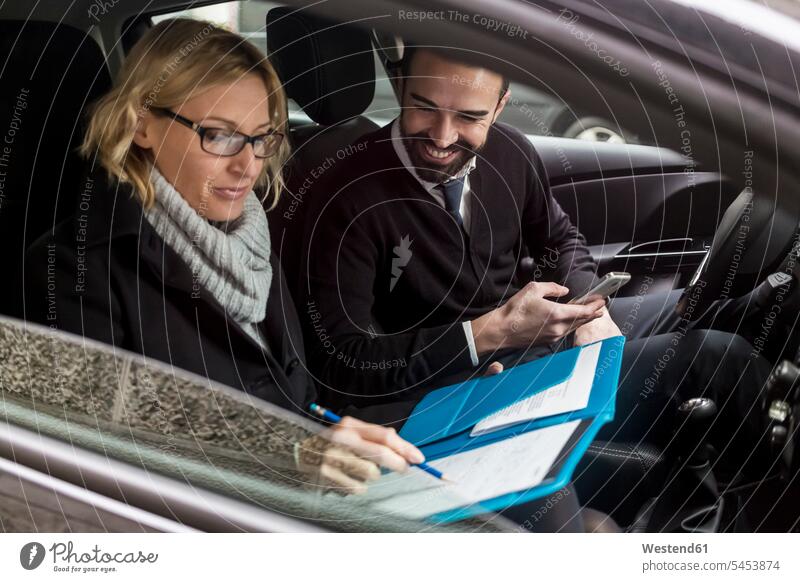 Businessman and businesswoman with documents in car on the move on the way on the go on the road businesswomen business woman business women Business man