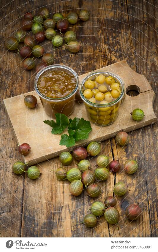 Jar of gooseberry jam, gooseberries and glass of preserved gooseberries on wooden board nobody large group of objects many objects uncooked fruit homemade