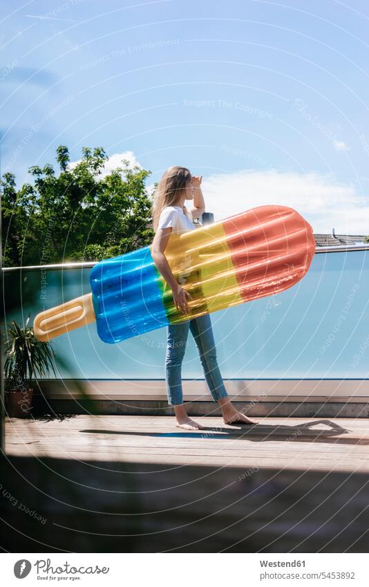 Young woman standing barefoot on balcony with an ice lolly shaped airbed Ice Lolly Iced Lolly Ice Lollies Iced-Lolly lilos airbeds air beds inflatable mattress