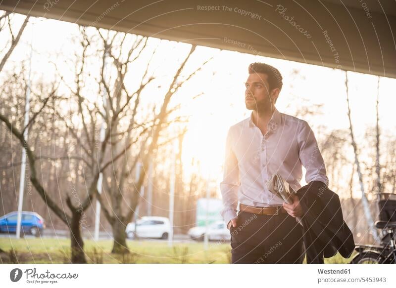 Young businessman with newspaper at sunset Businessman Business man Businessmen Business men waiting business people businesspeople business world business life