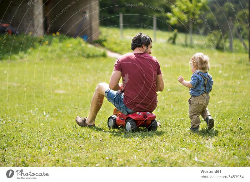 Father with his little son outside playing together sons manchild manchildren father pa fathers daddy dads papa garden gardens domestic garden family families