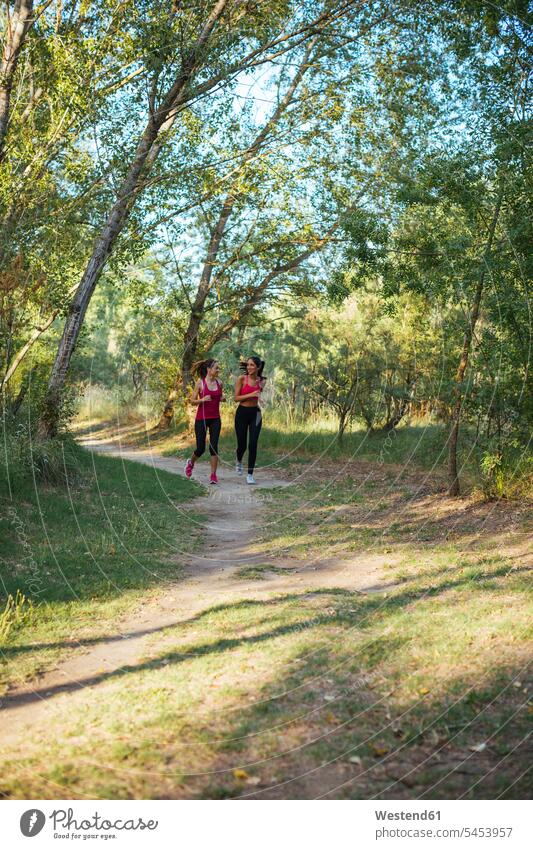 Two active women running in forest exercise exercises practising exercising woods forests woman females female friends Adults grown-ups grownups adult people