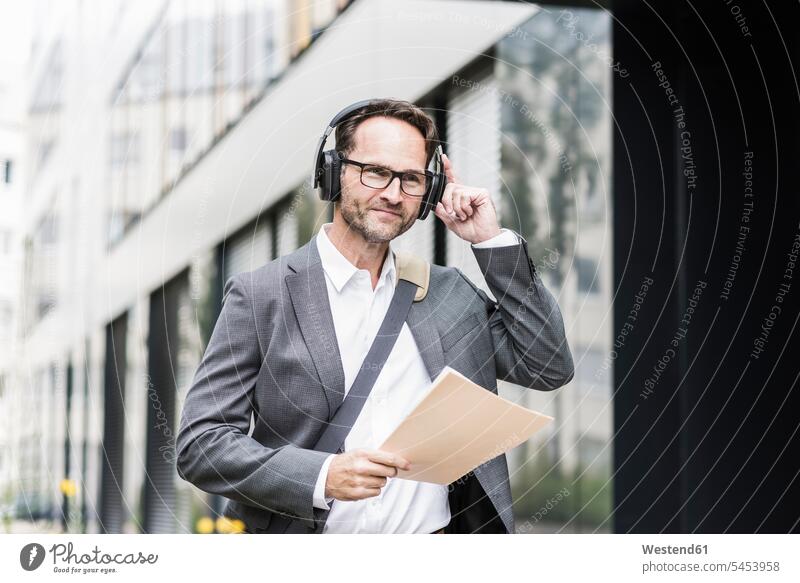Portrait of smiling businessman with documents and headphones Businessman Business man Businessmen Business men headset business people businesspeople