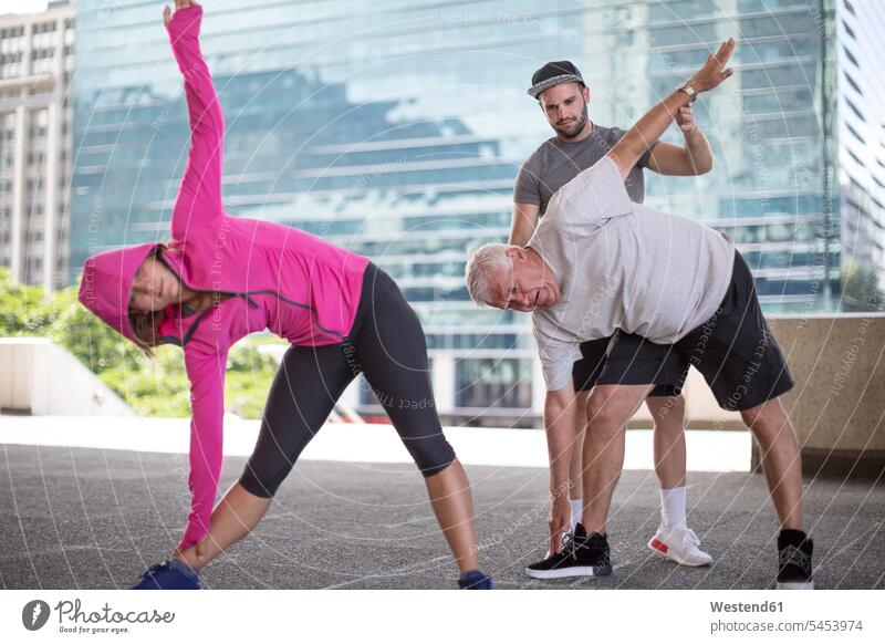 Fitness instructor guiding senior man doing a stretching exercise group groups athlete Sportspeople Sportsman Sportsperson athletes Sportsmen coach coaches
