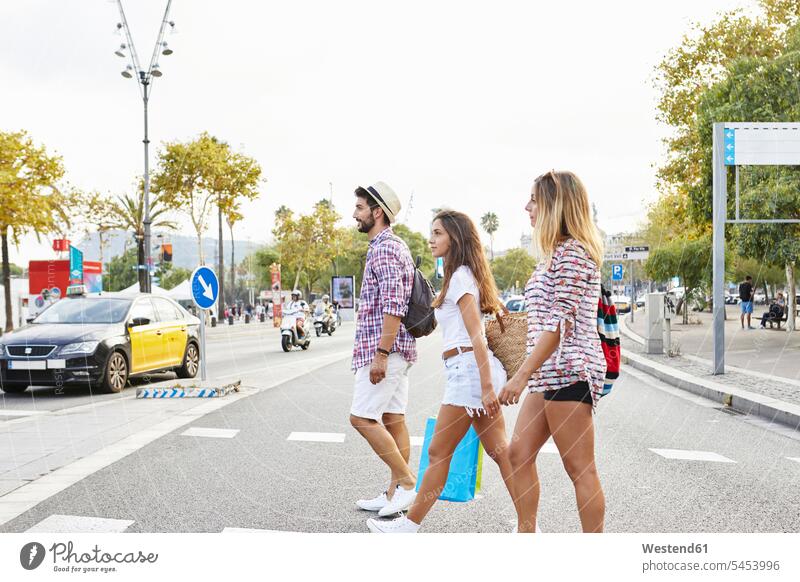 Three friends crossing a street road streets roads walking going mate friendship casual leisure wear casual clothing casual wear casual clothes Casual Attire