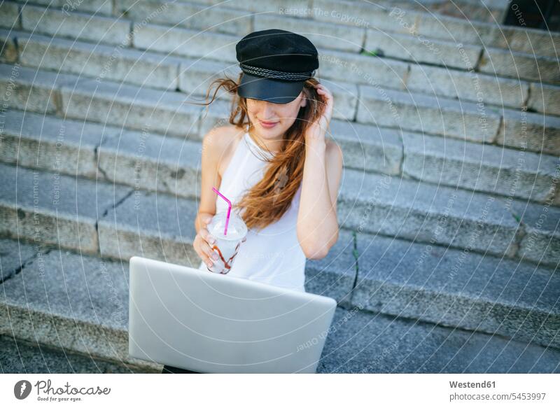 Young woman with laptop and smoothie sitting on steps females women Laptop Computers laptops notebook stairs stairway Adults grown-ups grownups adult people