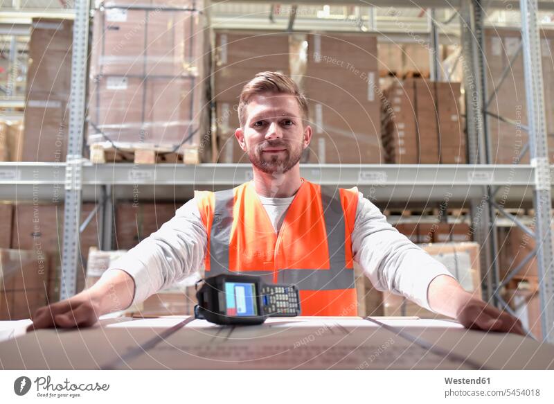 Portrait of confident man in factory hall with barcode scanner storehouse scanners men males working At Work storage warehouse building buildings Adults