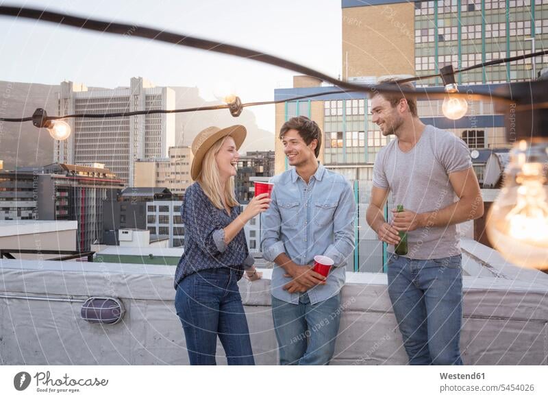 Friends having a rooftop party on a beautiful summer evening roof terrace deck together friends drinking enjoying indulgence enjoyment savoring indulging
