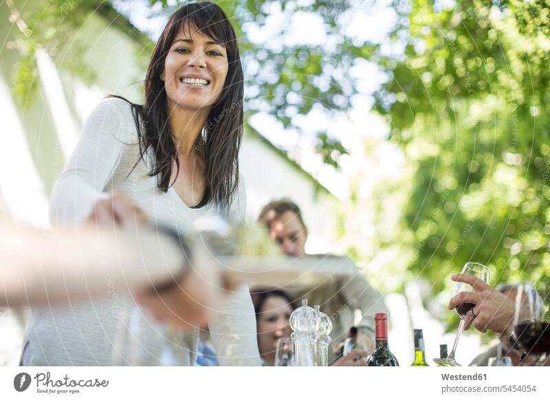 Smiling woman at family lunch in garden group of people Group groups of people Wine serving serve Red Wine Red Wines celebrating celebrate partying smiling