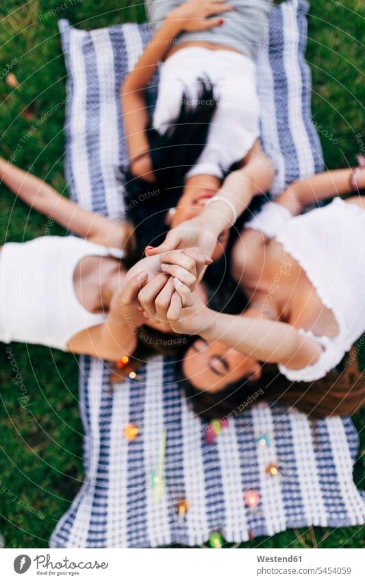 Friends in a park lying on blanket raising their arms laying down lie lying down female friends relaxed relaxation parks mate friendship relaxing community
