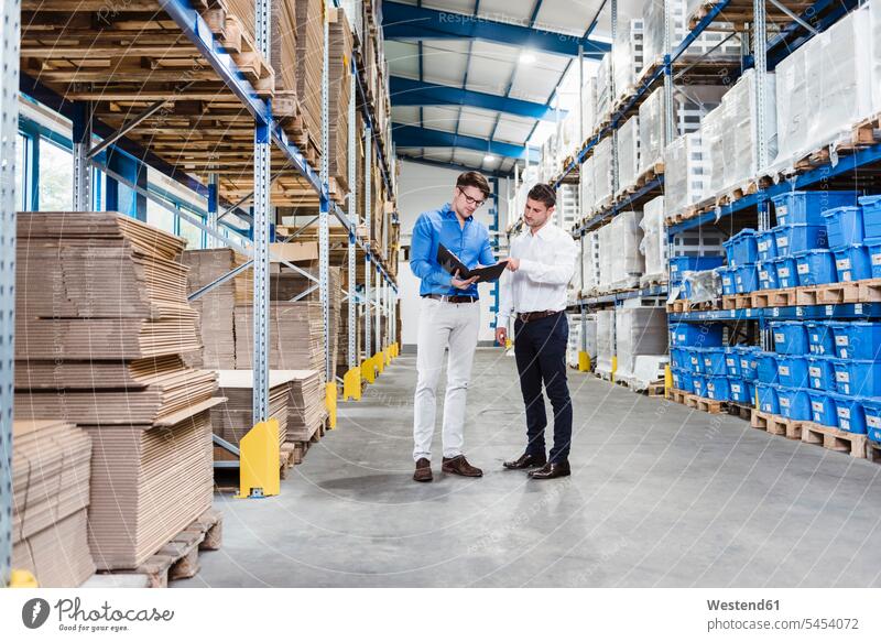 Two businessmen having a meeting in company warehouse Planning planning planned storehouse storage discussing discussion Business Meeting business conference