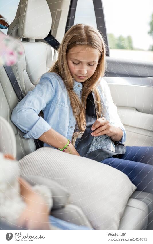 Girl sitting in car, fastening seat belt belted fastened Seated vacation Holidays Road Trip roadtrip Road-Trip safety belt girl females girls automobile Auto