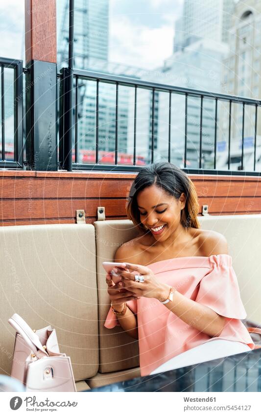 Smiling woman sending messages with her smartphone in the city mobile phone mobiles mobile phones Cellphone cell phone cell phones smiling smile females women