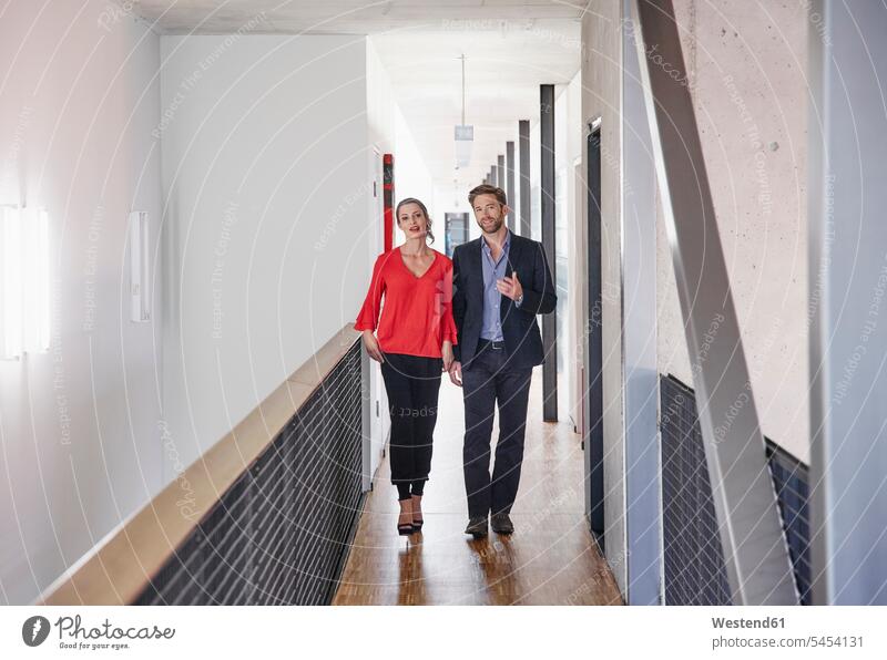 Businessman and businesswoman walking on office floor going Business man Businessmen Business men talking speaking offices office room office rooms