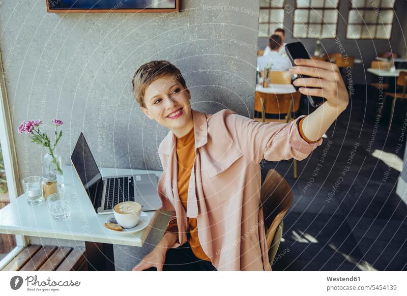 Woman taking a selfie with coffee and laptop in cafe smiling smile woman females women Laptop Computers laptops notebook Selfie Selfies mobile phone mobiles