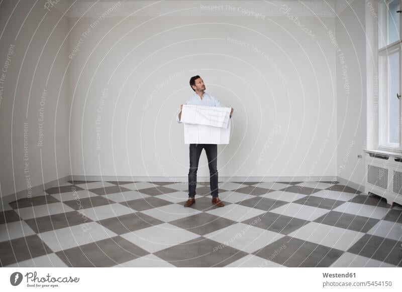 Man with construction plan in an empty room looking up man men males Adults grown-ups grownups adult people persons human being humans human beings watching