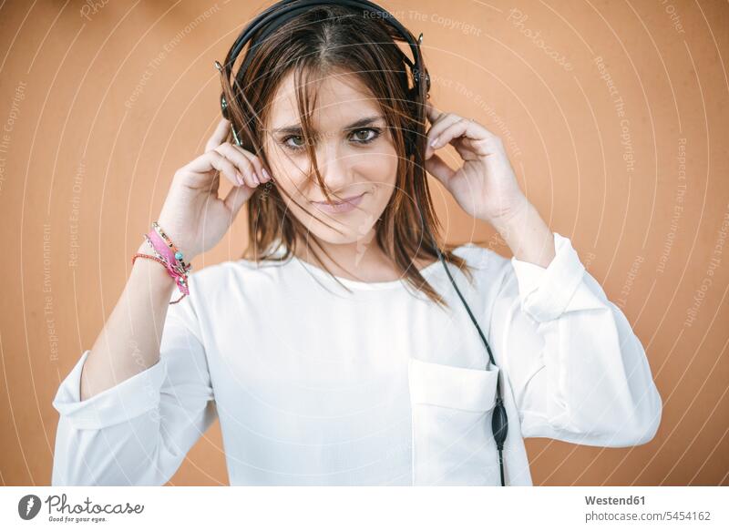 Portrait of smiling young woman listening music with headphones smile portrait portraits headset hearing females women Adults grown-ups grownups adult people