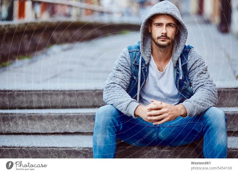 Serious man in hooded jacket sitting on stairs portrait portraits Seated serious earnest Seriousness austere men males Adults grown-ups grownups adult people