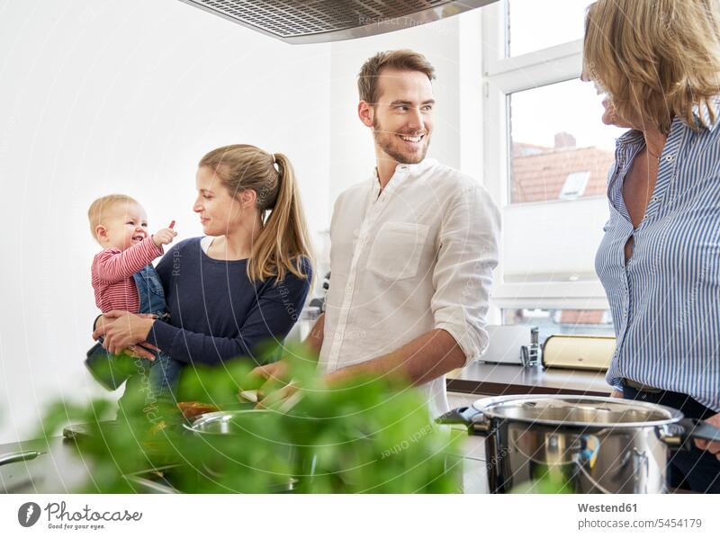 Family cooking in kitchen smiling smile domestic kitchen kitchens family families people persons human being humans human beings casual leisure wear