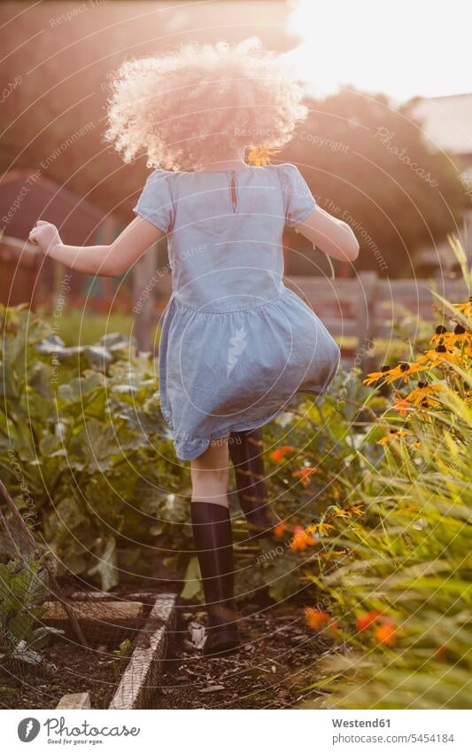 Back view of happy little girl jumping in the garden Flower Flowers females girls gardens domestic garden child children kid kids people persons human being
