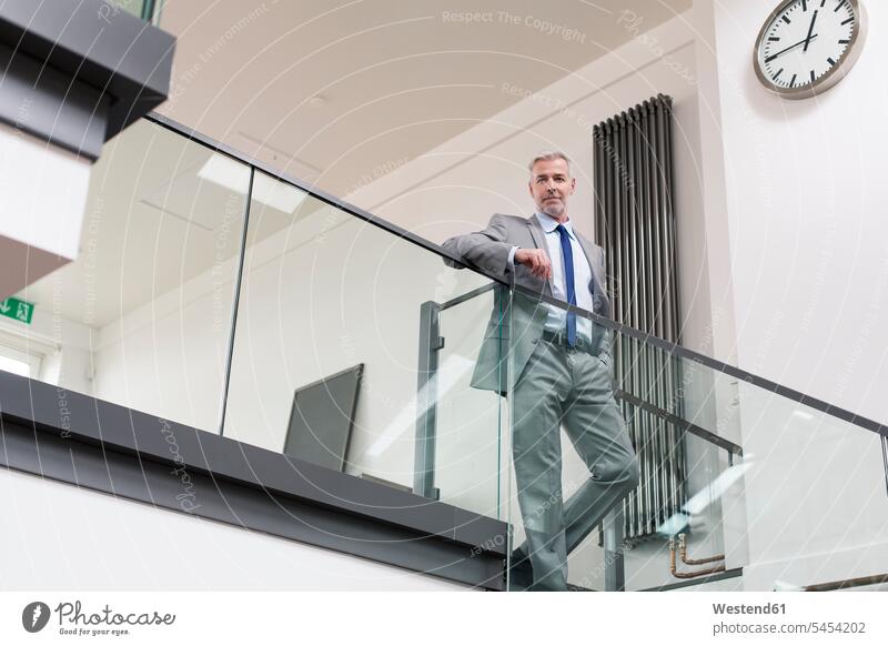 Mature businessman standing at railing in his office Businessman Business man Businessmen Business men offices office room office rooms Success successful