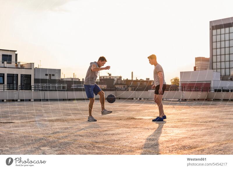 Friends playing basketball at sunset on a rooftop Fun having fun funny young basketballs fit Challenge challenging friends mate Basketball sport sports