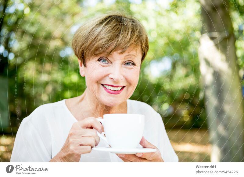 Portrait of smiling senior woman drinking cup of coffee outdoors senior women elder women elder woman old smile females Coffee senior adults Adults grown-ups