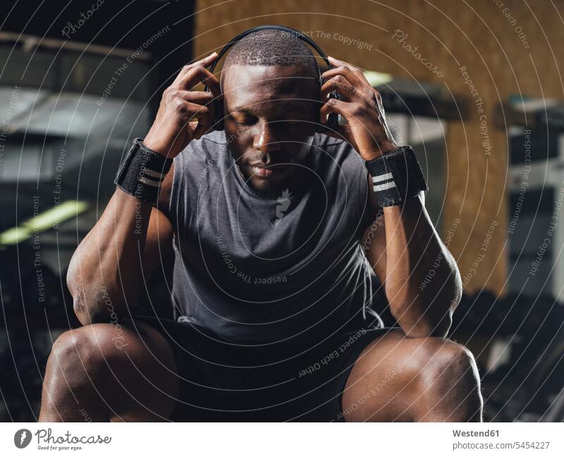 Athlete sitting in gym, wearing headphones, concentrating headset Muscular Build muscular muscles athletic gyms Health Club athlete Sportspeople Sportsman