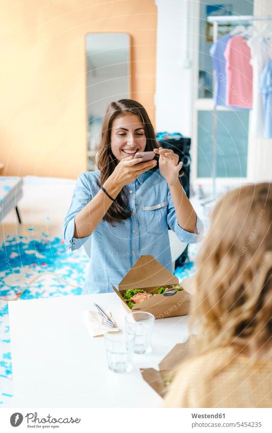 Happy young woman taking picture of takeaway salad on table Table Tables happiness happy mobile phone mobiles mobile phones Cellphone cell phone cell phones