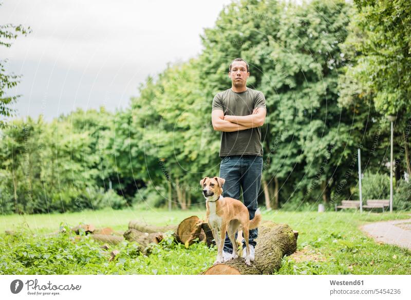 Portrait of serious man with dog in a park portrait portraits men males standing dogs Canine earnest Seriousness austere Adults grown-ups grownups adult people