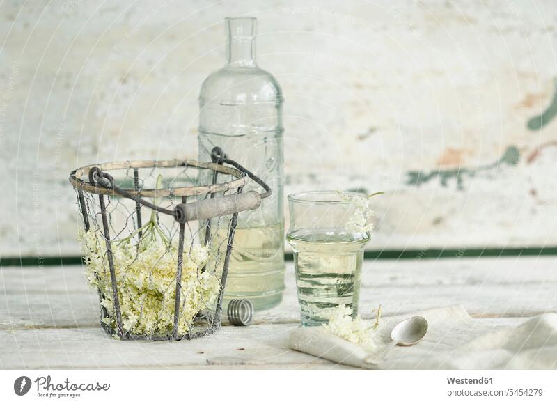Glass bottle and glass of elderflower sirup and elderflowers in wire basket food and drink Nutrition Alimentation Food and Drinks natural naturally liquid fluid